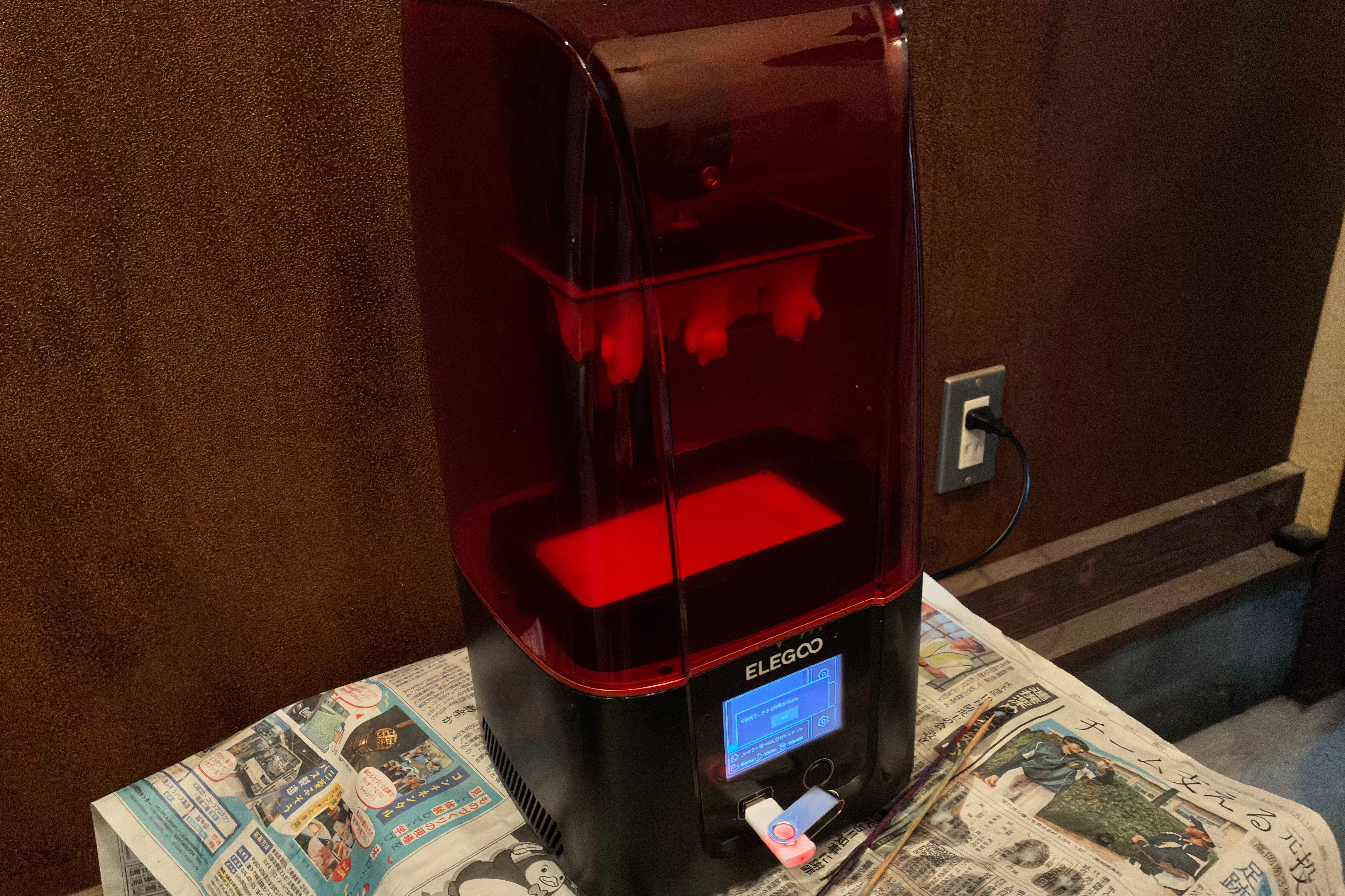 新聞の上に赤い3Dプリンター